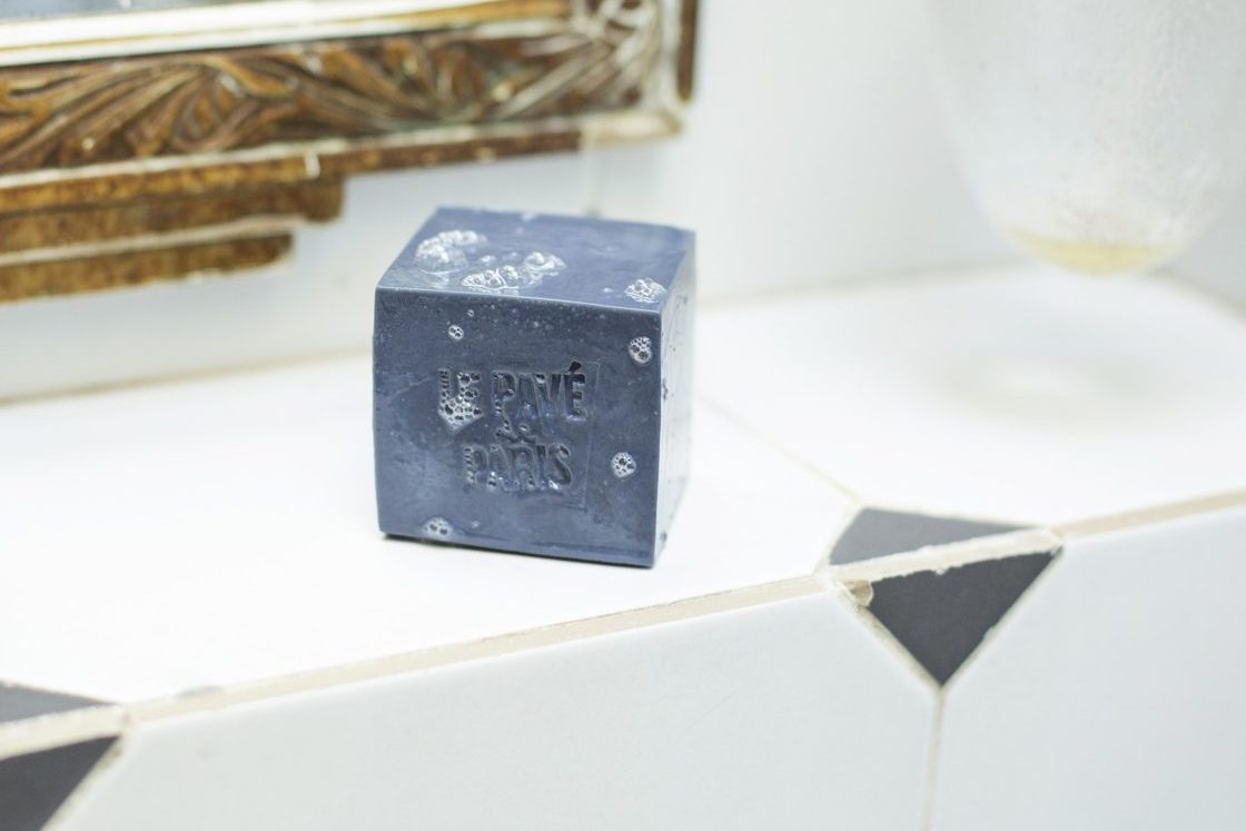 Le Bleu, pavé de savon à froid Atelier Populaire marqué « Le Pavé de Paris », posé sur le rebord carrelé d’un lavabo